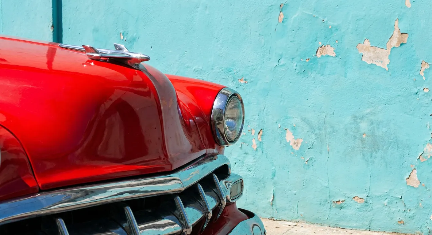 Gros plan iconique d'une voiture ancienne rouge devant un mur bleu turquoise à Cuba.