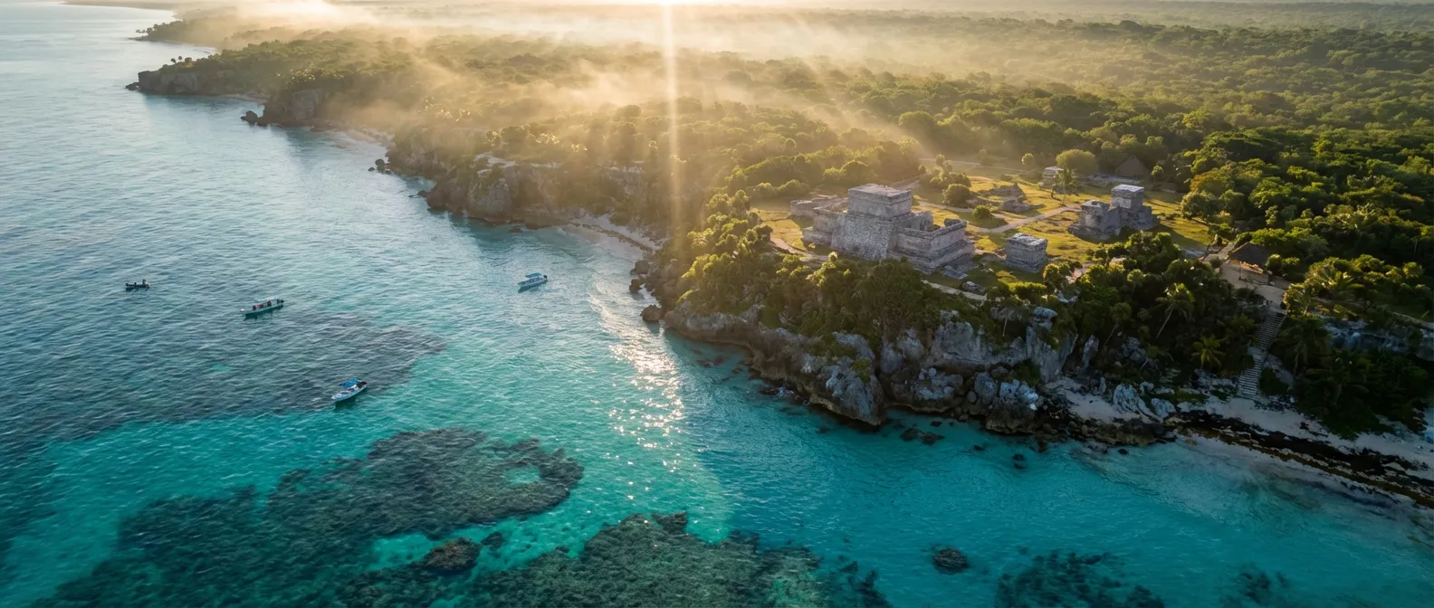 Vue aérienne panoramique des ruines de Tulum bordant la mer turquoise des Caraïbes au lever du soleil.